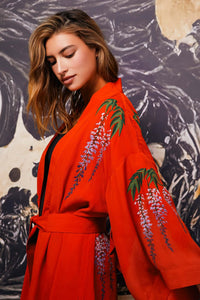 Model styles terracotta kimono robe embroidered with colourful wisteria and chrysanthemums over denim shorts and a black t-shirt