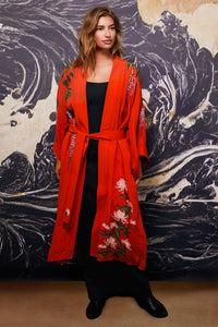 Model wears belted terracotta kimono style robe with wisteria and chrysanthemum embroidery over long black dress