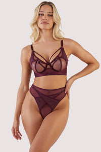 Harness style bra with mesh overlay and visible gold hardware in a deep wine red/purple, worn with a matching brief.