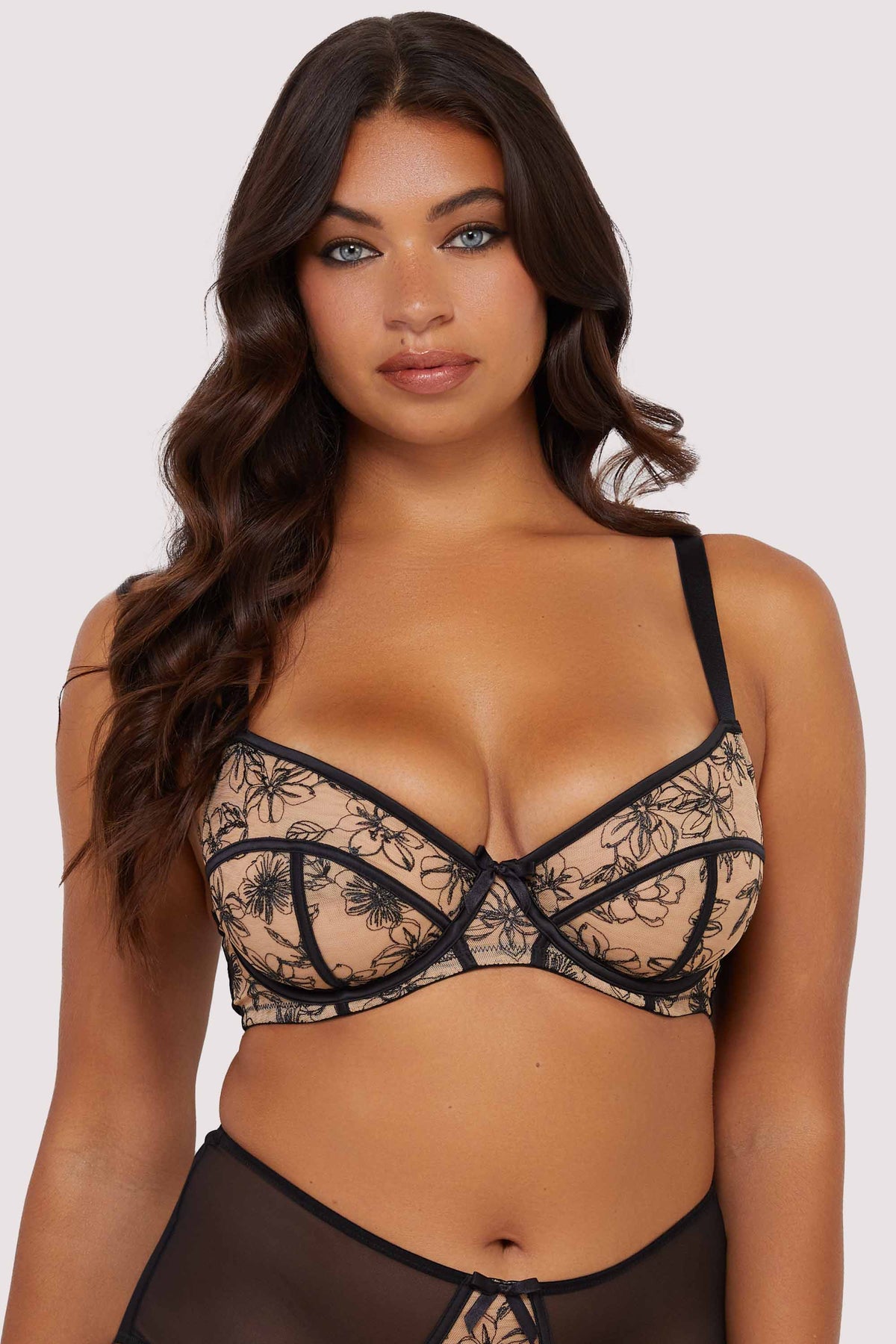 Model wears a black mesh balconette bra with floral embroidery details