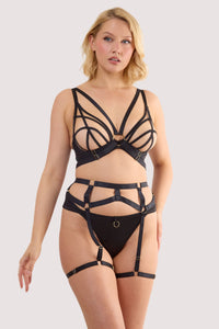 Model wears shows a back of black elastic suspender with gold metal accents and adjustable thigh harnesses